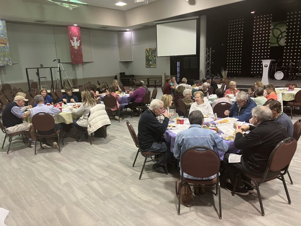 Adults gathered around tables for a Harrison fellowship meal