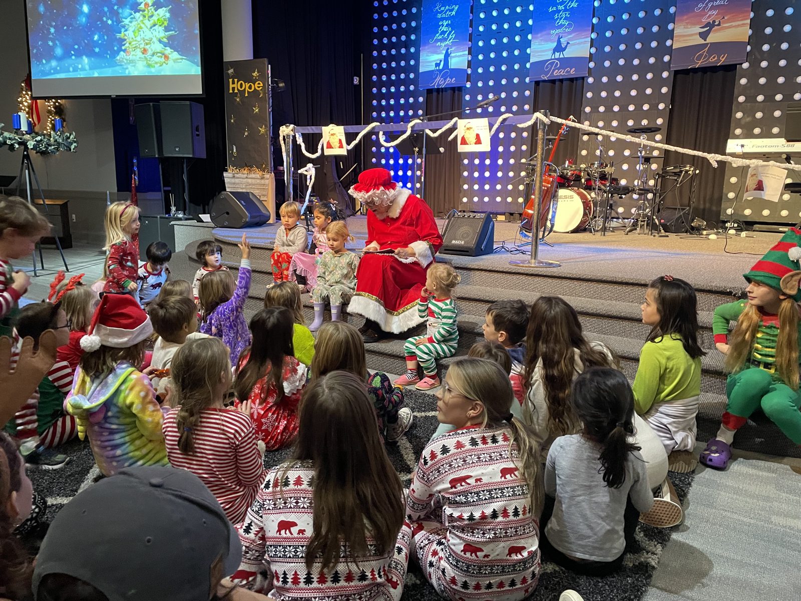 Children in Christmas pajamas gathered around Santa for a story