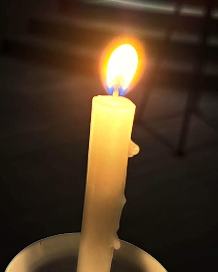 A single candle glowing during a Christmas candlelight service