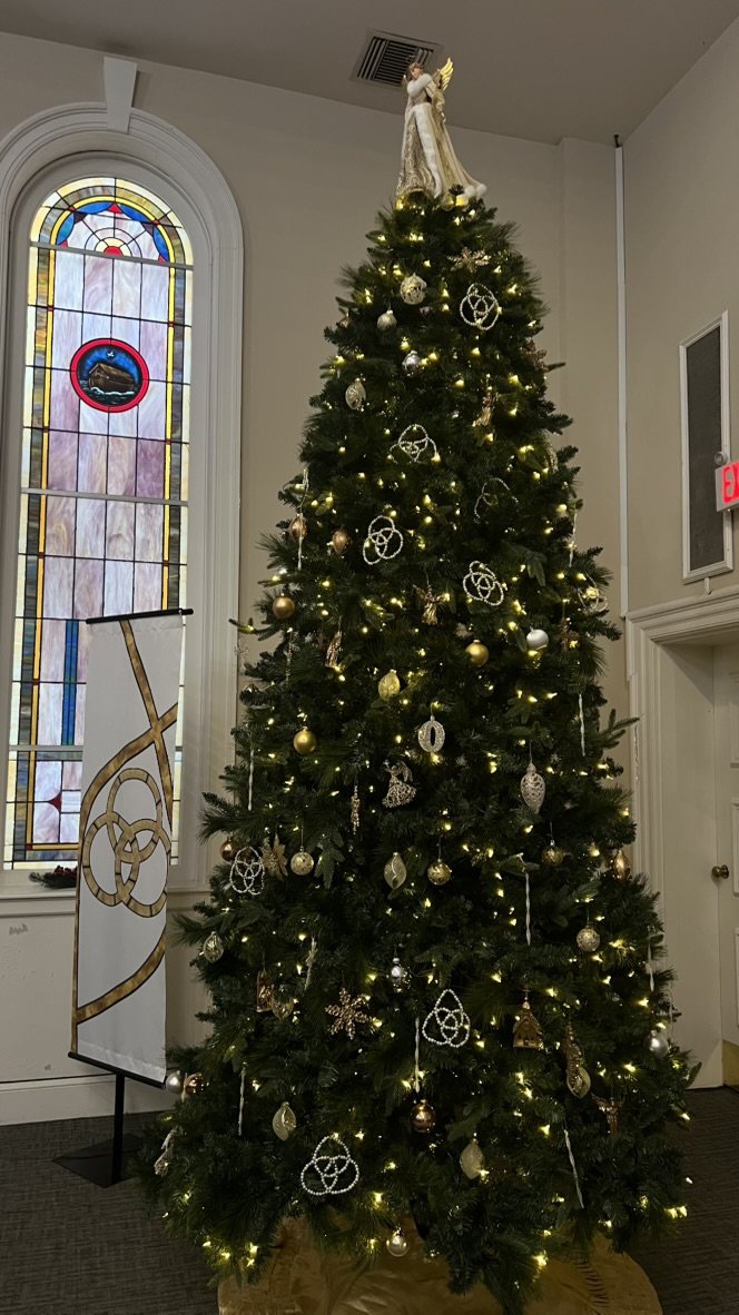 The sanctuary Christmas tree beside a stained glass window