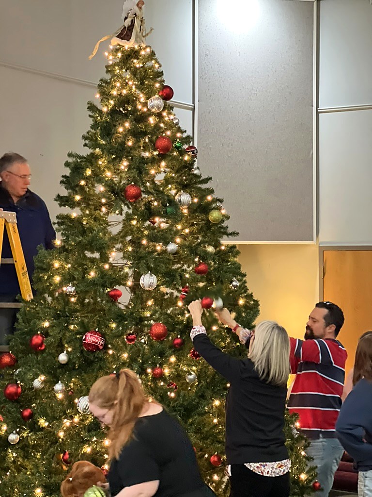 Church members of different ages decorating a Christmas tree together